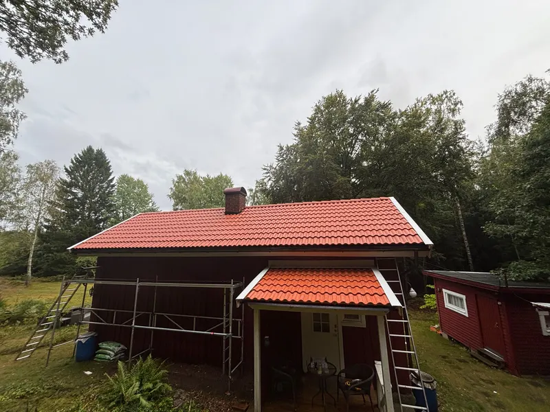 Rött hus med nylagt tak av röda takpannor och byggställning