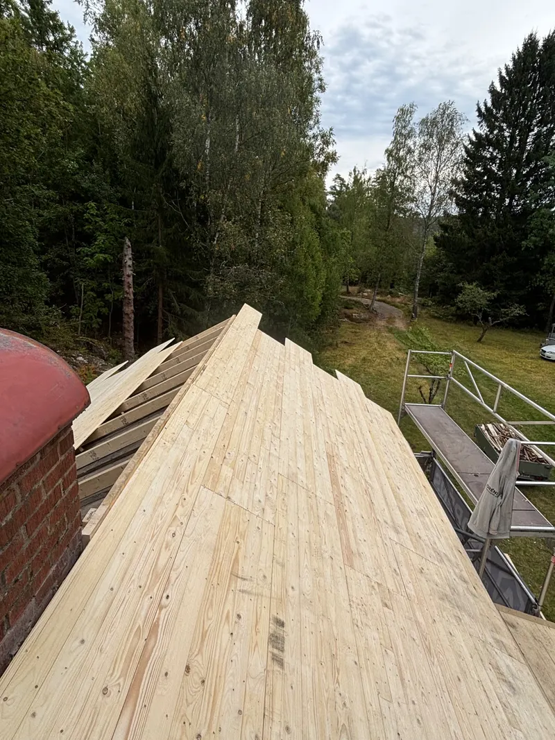 Nylagd råspont på taket intill skorstenen